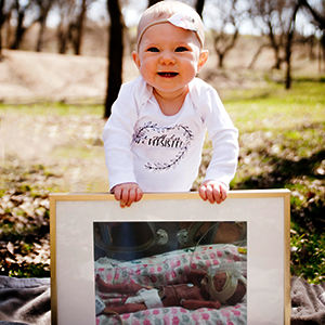 Baby outdoors leaning on a framed photo